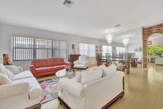 living room featuring a healthy amount of sunlight, light wood-type flooring, and a chandelier