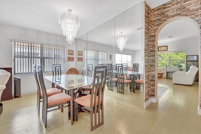 dining space with plenty of natural light, light hardwood / wood-style floors, and a notable chandelier