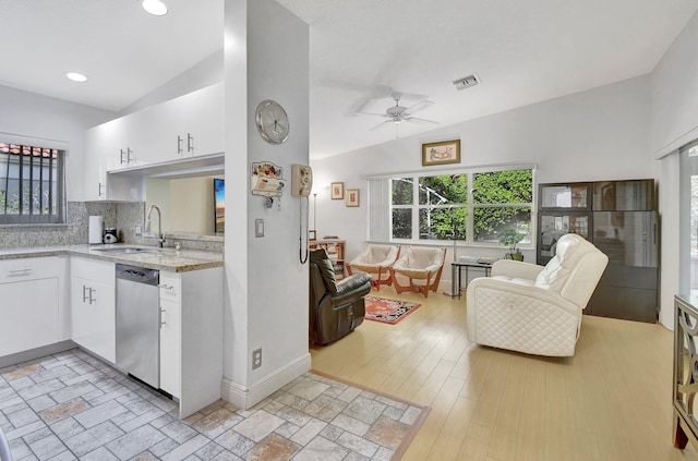 kitchen with stainless steel dishwasher, vaulted ceiling, sink, white cabinets, and light hardwood / wood-style floors