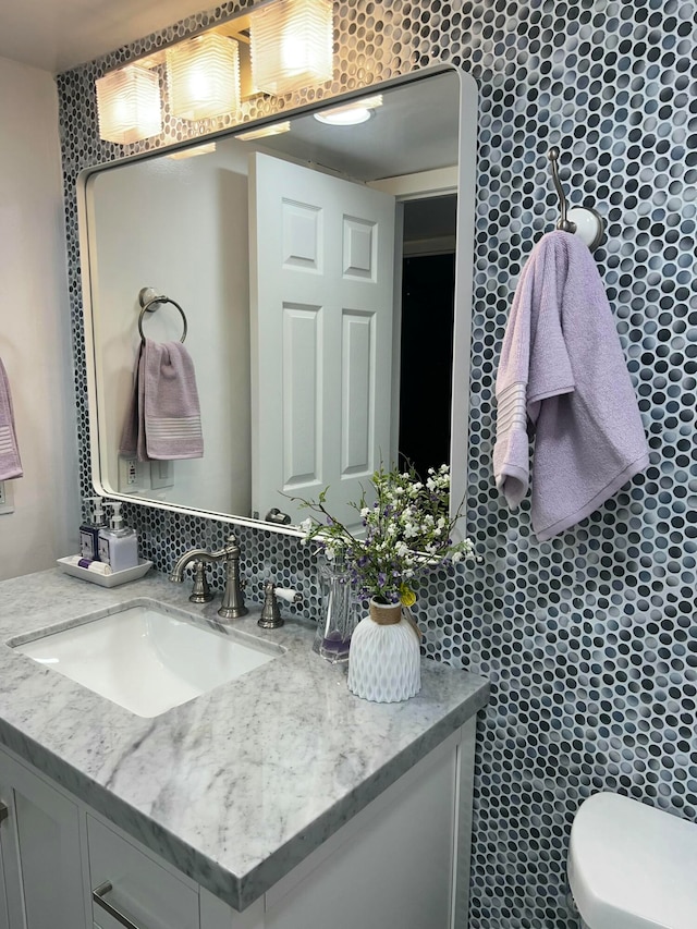 bathroom with decorative backsplash, vanity, toilet, and tile walls