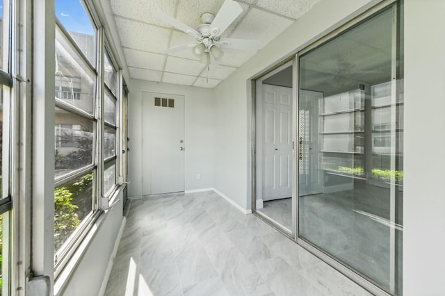 unfurnished sunroom featuring a paneled ceiling and ceiling fan