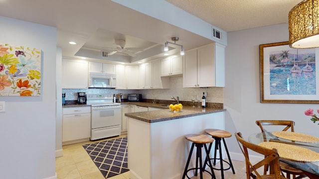 kitchen featuring ceiling fan, sink, kitchen peninsula, white appliances, and white cabinets