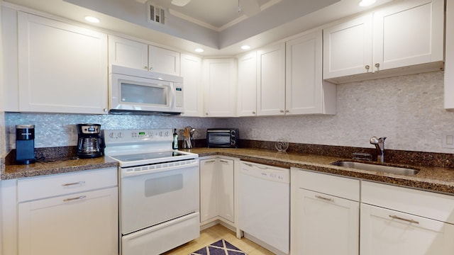 kitchen featuring white appliances, white cabinetry, dark stone counters, and sink