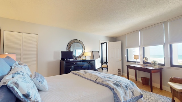 bedroom with wood-type flooring, a textured ceiling, and a closet