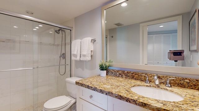 bathroom featuring vanity, a shower with shower door, and toilet