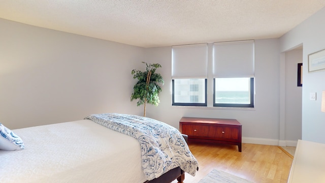 bedroom with light hardwood / wood-style floors and a textured ceiling