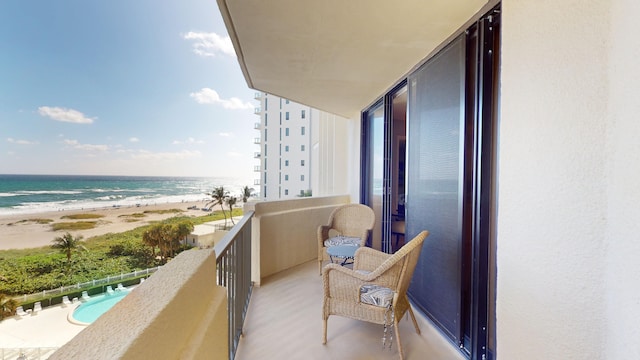 balcony featuring a view of the beach and a water view