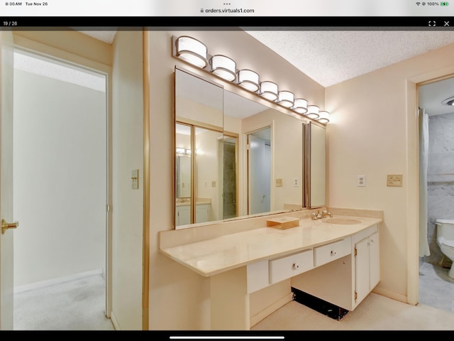 bathroom with vanity, toilet, and a textured ceiling