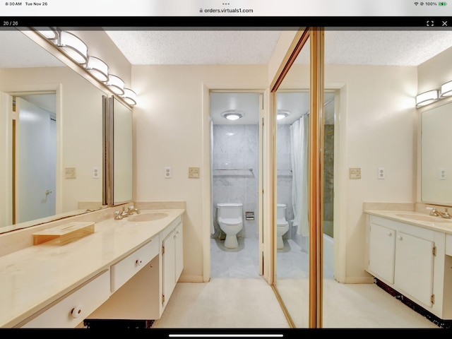 full bathroom with vanity, a textured ceiling, toilet, and tiled shower / bath combo