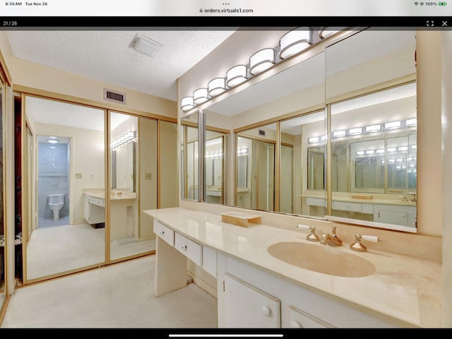 bathroom with vanity, a textured ceiling, and toilet