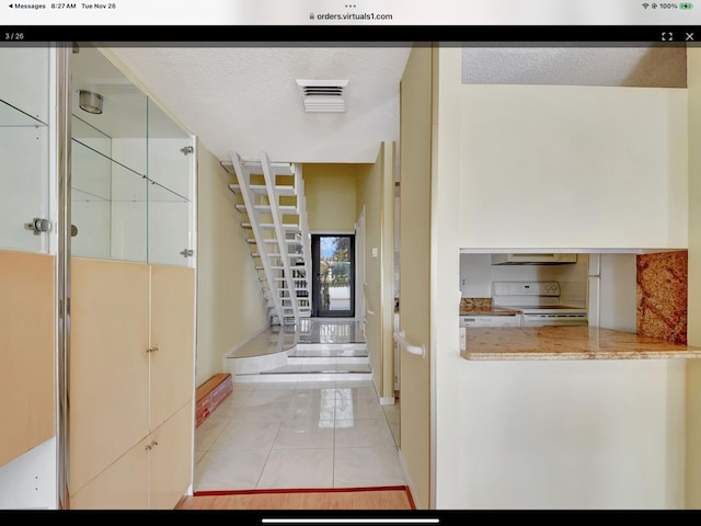 hallway with light tile patterned floors and a textured ceiling