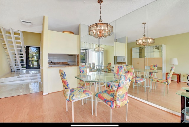 dining space with light wood-type flooring, sink, and a chandelier