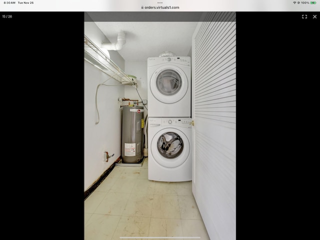 washroom with stacked washer / dryer and water heater