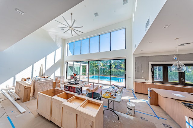 kitchen featuring a center island, a high ceiling, hanging light fixtures, ceiling fan, and light brown cabinetry