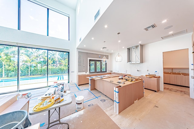 kitchen with pendant lighting, a center island, and a towering ceiling