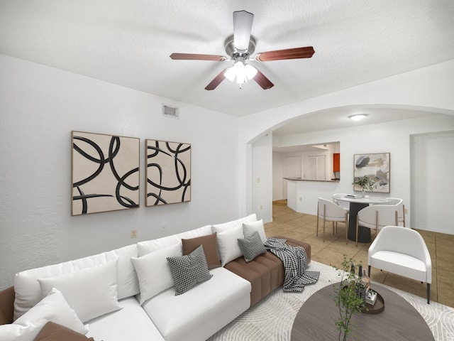 living room featuring ceiling fan, light tile patterned floors, and a textured ceiling