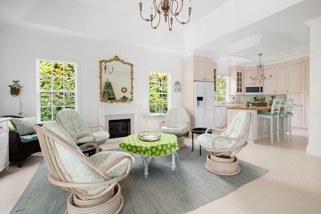 3645 Ocean Dr, Vero Beach, FL 32963 - living area featuring a chandelier, a raised ceiling, a glass covered fireplace, ornamental molding, and light wood-style flooring