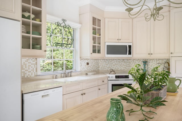 3645 Ocean Dr, Vero Beach, FL 32963 - kitchen featuring white appliances, a chandelier, ornamental molding, decorative backsplash, and glass insert cabinets