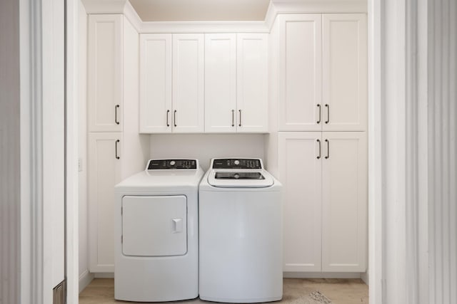 laundry area with cabinets, light hardwood / wood-style flooring, and washer and dryer