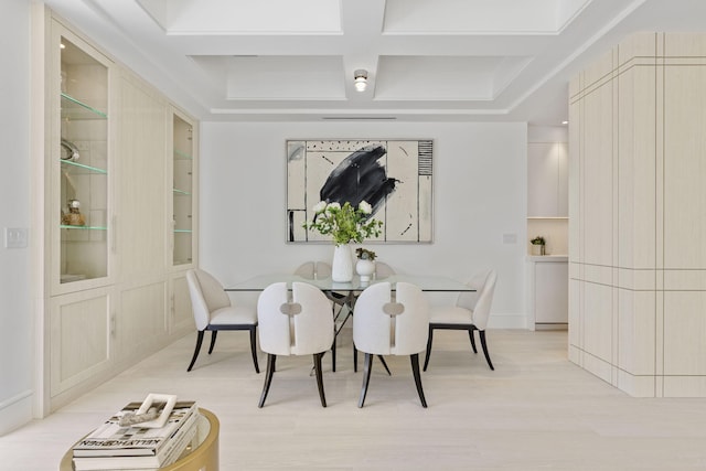 dining space with coffered ceiling and light hardwood / wood-style floors