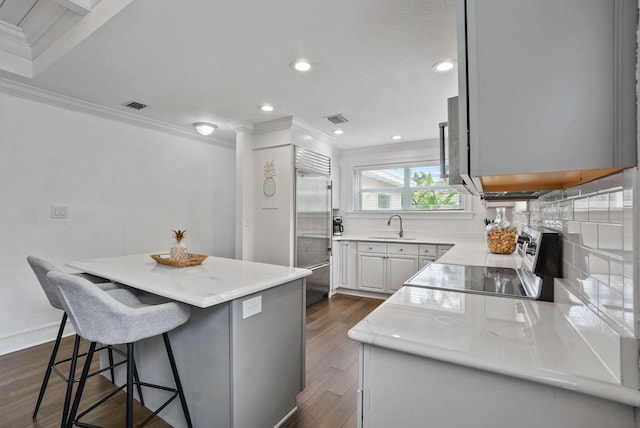 kitchen with sink, dark hardwood / wood-style flooring, backsplash, a kitchen island, and ornamental molding