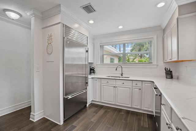 kitchen with dark hardwood / wood-style flooring, stainless steel appliances, crown molding, sink, and white cabinets