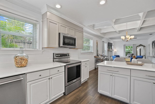 kitchen featuring an inviting chandelier, dark hardwood / wood-style floors, appliances with stainless steel finishes, decorative light fixtures, and beam ceiling