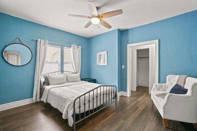 bedroom with ceiling fan, dark hardwood / wood-style flooring, a spacious closet, and a closet