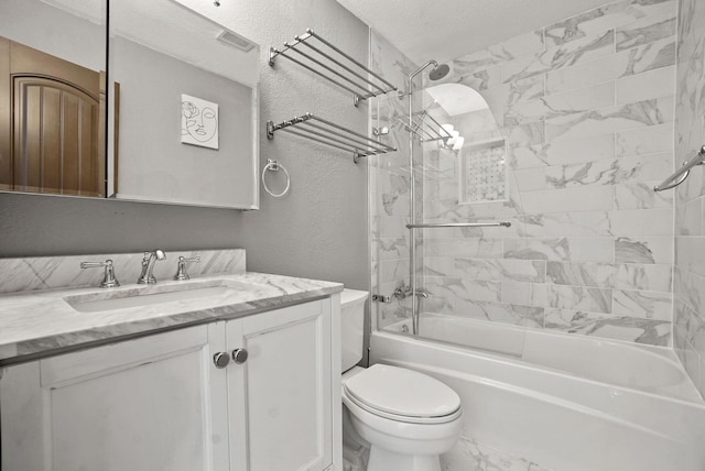 full bathroom with vanity, a textured ceiling, tiled shower / bath combo, and toilet