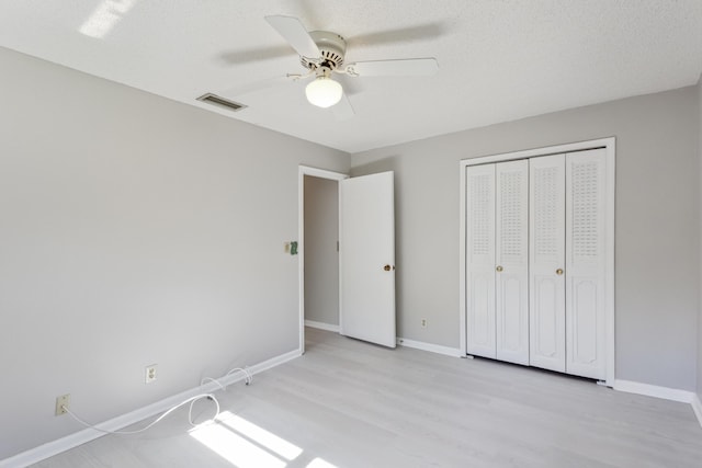 unfurnished bedroom featuring a textured ceiling, a closet, light hardwood / wood-style flooring, and ceiling fan