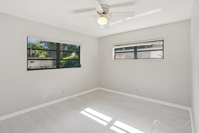 spare room featuring a textured ceiling, light hardwood / wood-style floors, plenty of natural light, and ceiling fan