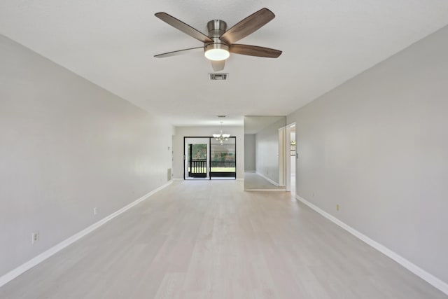 spare room with ceiling fan with notable chandelier and light wood-type flooring