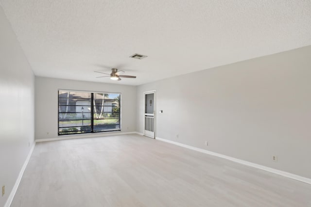 empty room with a textured ceiling, light wood-type flooring, and ceiling fan