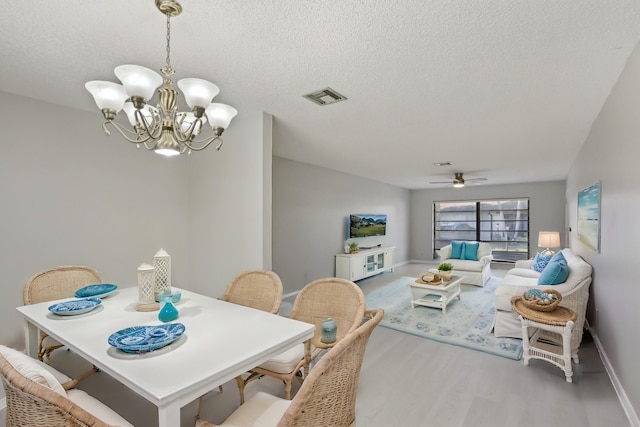 dining area with a textured ceiling, ceiling fan with notable chandelier, and light hardwood / wood-style floors