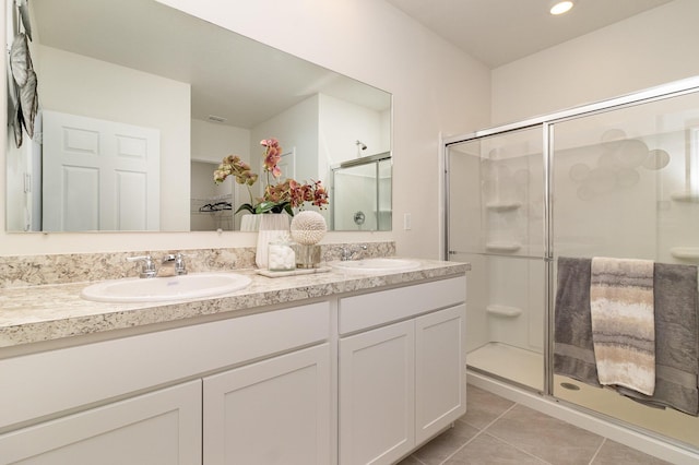full bath featuring a shower stall, tile patterned floors, double vanity, and a sink