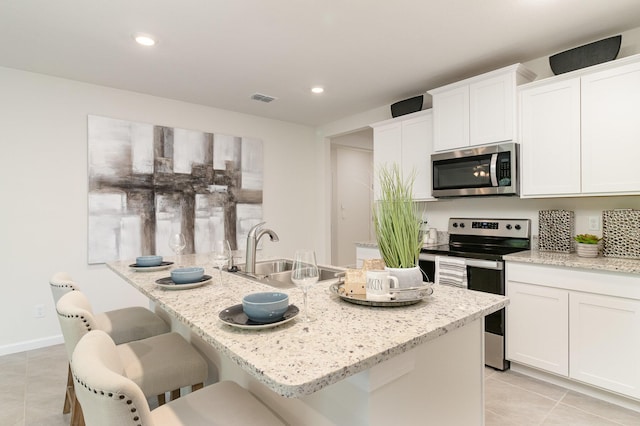 kitchen with light tile patterned floors, white cabinets, visible vents, appliances with stainless steel finishes, and a sink