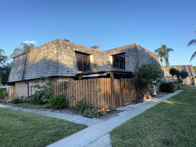 view of property exterior with a lawn and a balcony