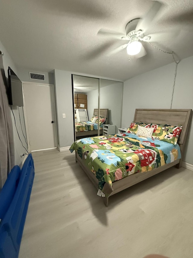 bedroom featuring hardwood / wood-style flooring, ceiling fan, a textured ceiling, and a closet