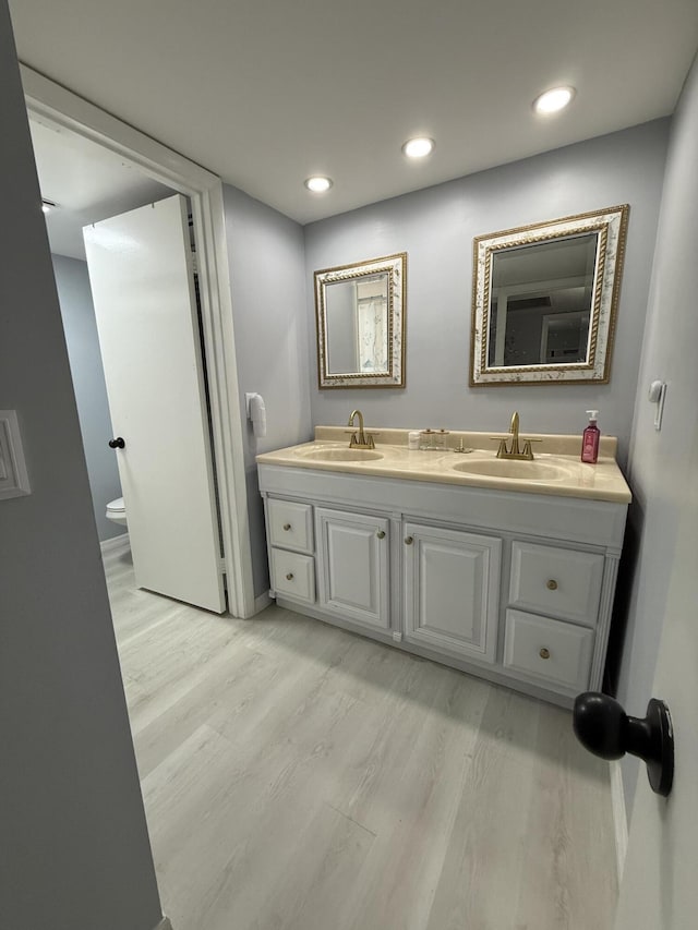 bathroom featuring wood-type flooring, toilet, and vanity