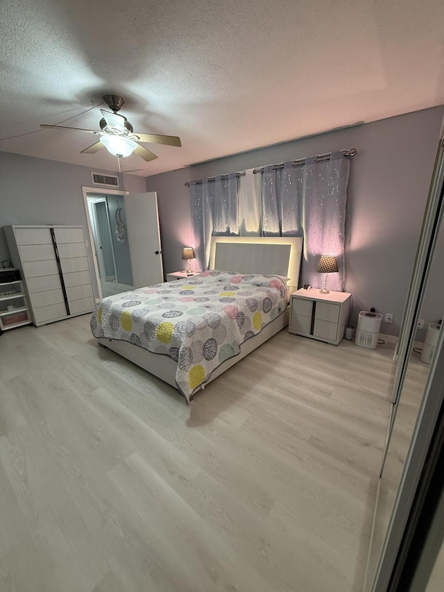 bedroom featuring ceiling fan, a textured ceiling, and light wood-type flooring