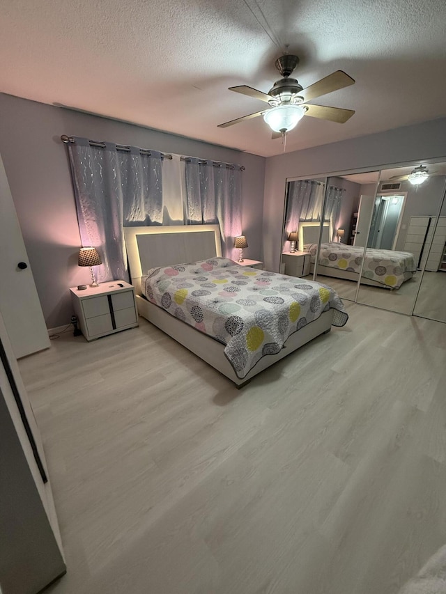 bedroom featuring ceiling fan, a textured ceiling, and light wood-type flooring