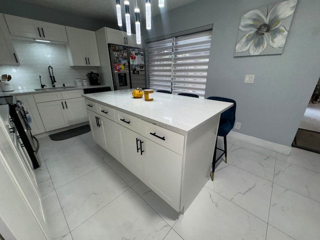 kitchen with stainless steel fridge, backsplash, a kitchen island, sink, and white cabinetry