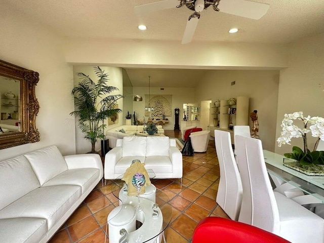 living room featuring vaulted ceiling, ceiling fan, dark tile patterned floors, and a textured ceiling