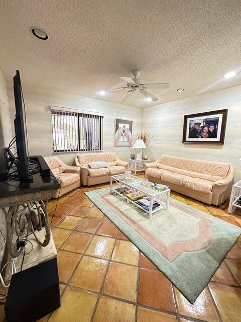 living room featuring tile patterned flooring, a textured ceiling, and ceiling fan