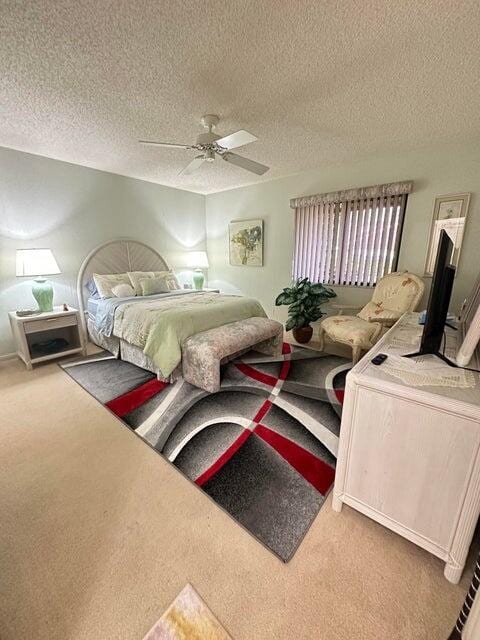 bedroom with ceiling fan, carpet floors, and a textured ceiling