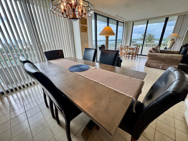 tiled dining space with a textured ceiling, an inviting chandelier, and expansive windows