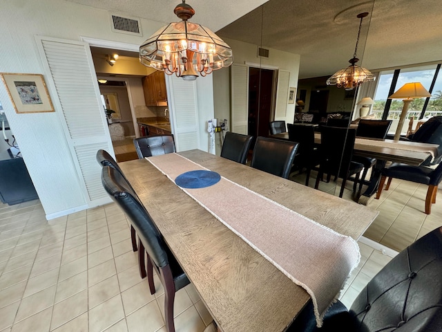 dining room featuring light tile patterned flooring, a textured ceiling, and an inviting chandelier