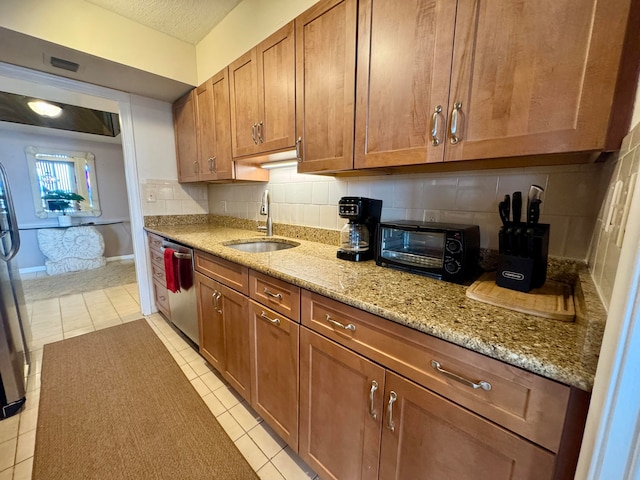 kitchen featuring tasteful backsplash, dishwasher, sink, and light tile patterned flooring