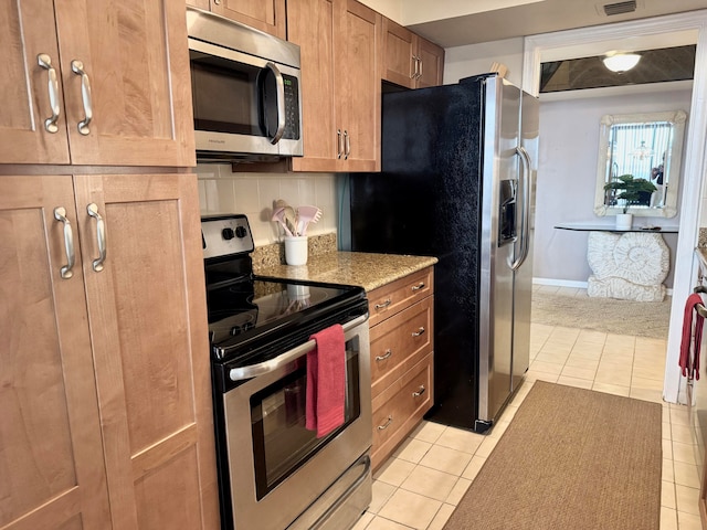 kitchen featuring light stone countertops, light tile patterned floors, backsplash, and appliances with stainless steel finishes