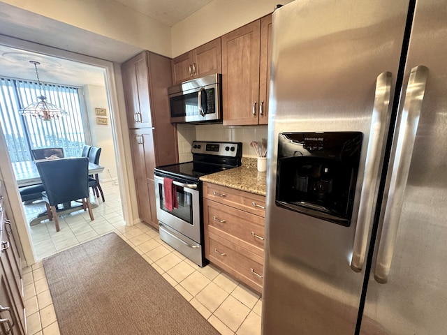 kitchen featuring backsplash, hanging light fixtures, light tile patterned floors, appliances with stainless steel finishes, and a chandelier